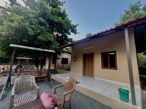 un patio con 2 sillas y una casa en Tejas Gir Villa, en Sasan Gir
