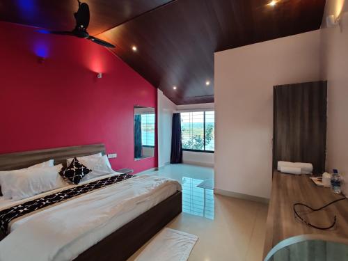 a bedroom with a large bed with a red wall at Neel Farms and Resort in Saoner