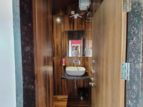 a bathroom with a sink and a wooden wall at Neel Farms and Resort in Saoner