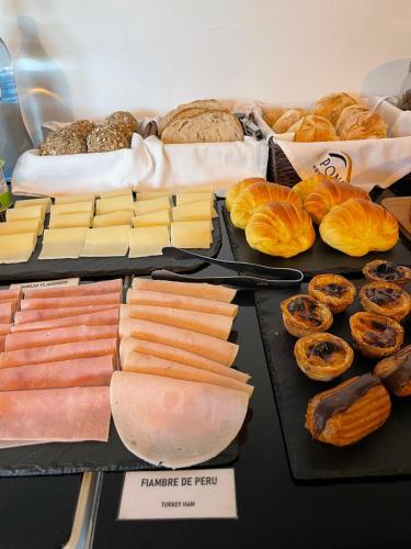 une table avec différents types de fromages et de pains dans l'établissement Hotel A Ponte, à Viana do Castelo
