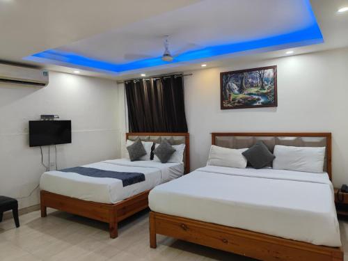 JāmbにあるHotel Royal Plaza At IGI Airportのブルー天井のホテルルーム内のベッド2台