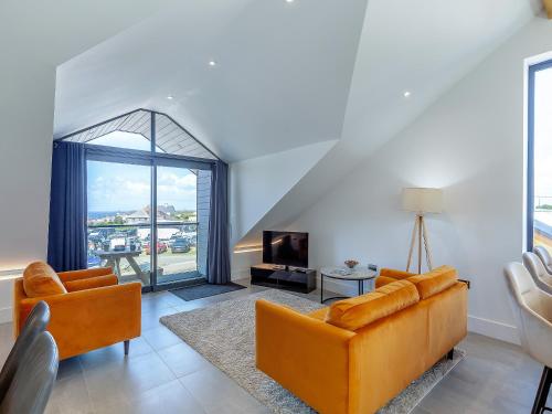 Una sala de estar con dos sofás naranjas y un televisor. en Sea Skapya - Uk50178, en Helston