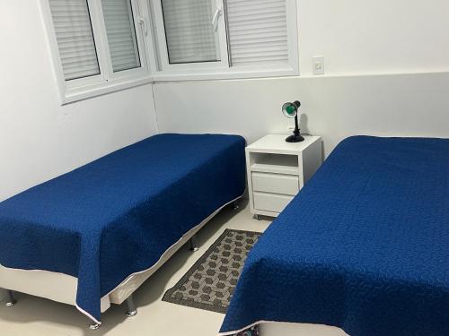 2 letti in una camera con coperte blu di Cobertura com jacuzzi e churrasqueira privada - Praia dos Ingleses a Florianópolis