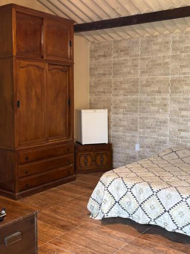 a bedroom with a bed and a large wooden cabinet at Chácara do Conde in Mangaratiba