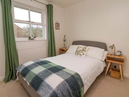 a bedroom with a bed with green curtains and a window at Lair Close House in Harrogate