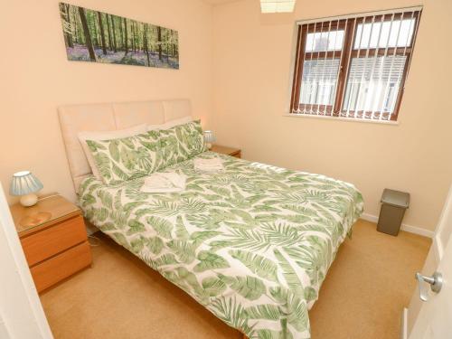 een slaapkamer met een bed met een groen en wit dekbed bij Poole Quay Cottage in Poole