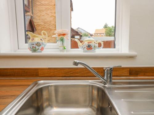 a kitchen sink with three vases on a window sill at Harbour View Poole in Poole