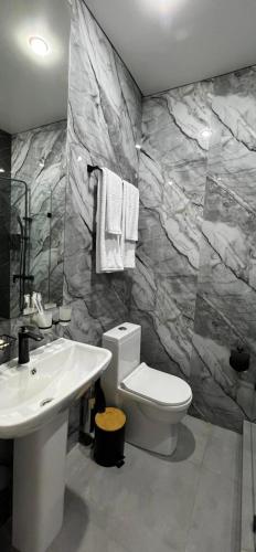 a bathroom with a white toilet and a sink at Van park hotel in Shymkent