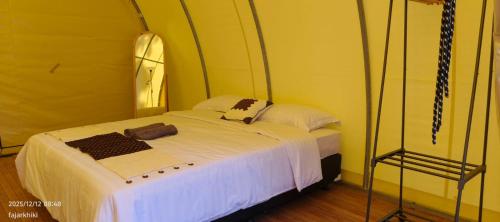 a small room with a bed with white sheets at Kayi glamping in Kaliurang