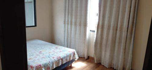 ein Schlafzimmer mit einem Bett und einem Fenster mit Vorhängen in der Unterkunft Casa de 01 quarto para temporada in Marataizes