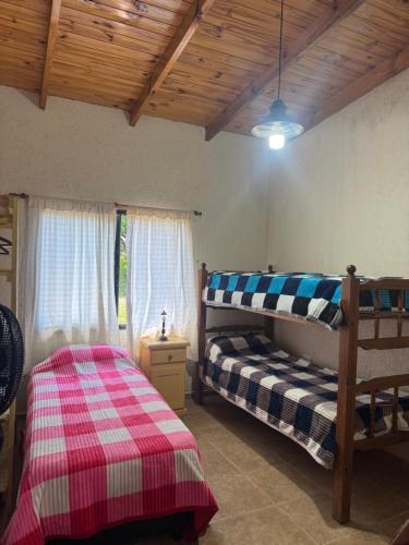 een slaapkamer met twee bedden en een houten plafond bij Cabaña Zara in Villa Yacanto
