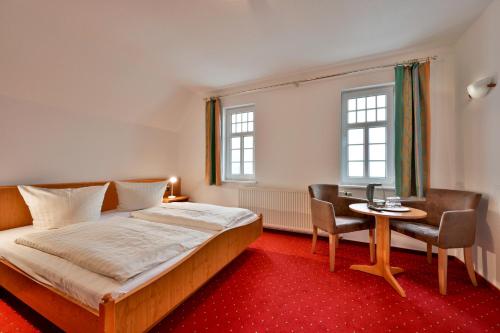 een slaapkamer met een bed, een tafel en stoelen bij Hotel Waldschlösschen und Spezialitätenrestaurant in Oberhof