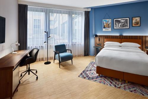 a hotel room with a bed and a desk and chair at Four Points by Sheraton Munich Messe in Munich