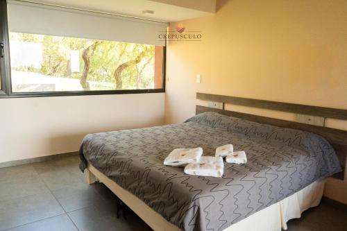 a bedroom with a bed with two towels on it at Crepúsculo Serrano in Merlo
