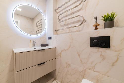 een badkamer met een wastafel en een spiegel bij ENZO Apartments in Šiauliai