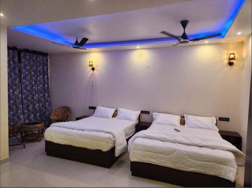 two beds in a room with a blue light at Coffee valley resort Yercaud CVR in Yercaud