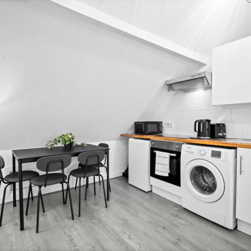 a kitchen with a table and a washing machine at Modern Apartment - Accommodates 4 - On Street Parking - Neftlix 2CR in Birmingham