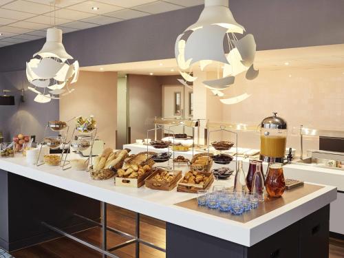 a bakery counter with a bunch of pastries and desserts at Novotel Coventry in Coventry