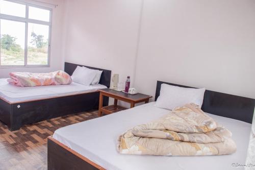 ein Schlafzimmer mit zwei Betten und einem Fenster in der Unterkunft SILVERBERRY Homestay in Kalimpong