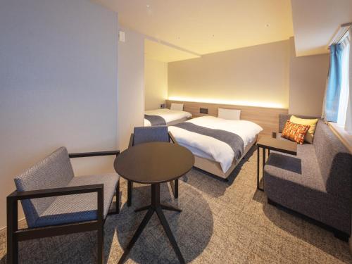 a hotel room with two beds and a table and chair at New Osaka Hotel in Osaka