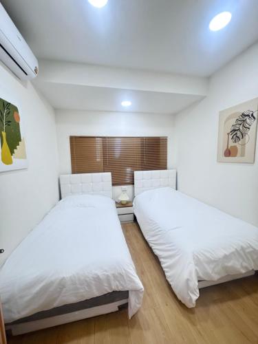 twee bedden in een slaapkamer met witte muren en houten vloeren bij Sun Sun Hostel in Pai