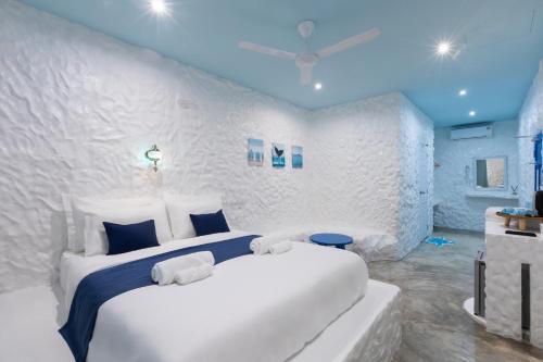 a white bedroom with a large bed with blue ceilings at Sweett Lemon Home in Patong Beach