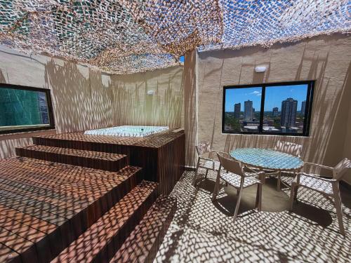 Habitación con camas, mesa y ventana en ApartDamani - Aptos por Temporada en el centro, en Foz do Iguaçu