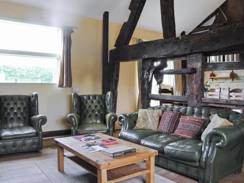 een woonkamer met een leren bank en 2 stoelen bij Hirros Hall Longhouse in Llanerfyl