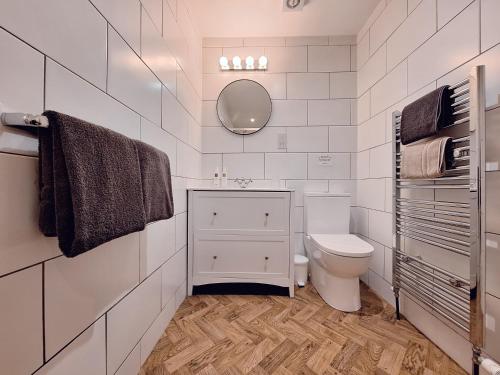 een witte badkamer met een toilet en een spiegel bij The Mews Room at The Coach House in Windermere