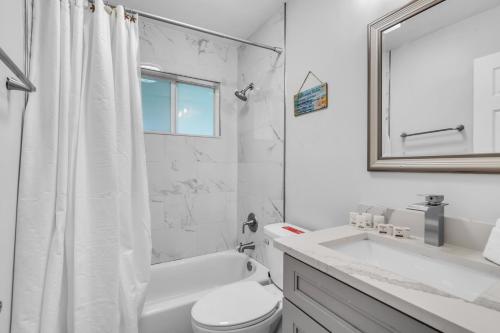 Un baño blanco con inodoro y lavabo. en Private Pool Vacation Home Near Beach Newly Renovated, en Deerfield Beach