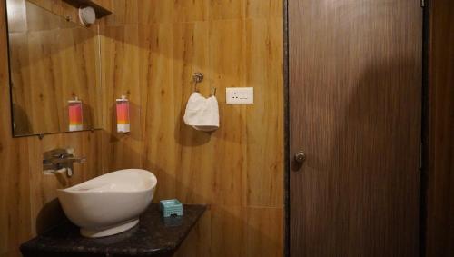 een badkamer met een toilet en een wastafel tegen een houten muur bij Silver Green Resort in Gumgaon