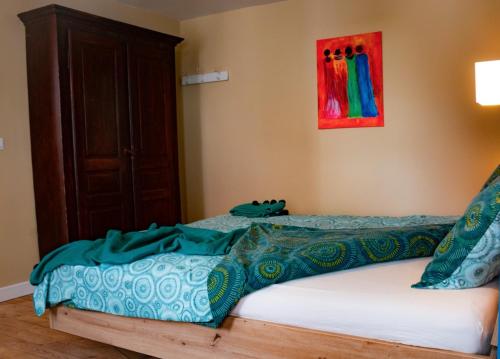 een slaapkamer met een bed met blauwe en groene lakens bij Au Vent des Blés in Incourt