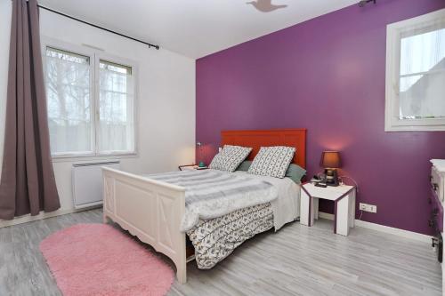 une chambre avec un lit et un mur violet dans l'établissement L'écrin sous les chênes - Wifi - Jardin, à Olivet