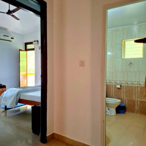 a bathroom with a bed and a toilet in a room at Casa Bela in Canacona