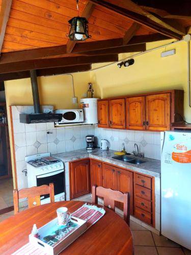a kitchen with a table and a white refrigerator at CASA los ciruelos in El Bolsón