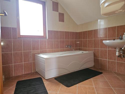 ein Badezimmer mit Badewanne und Waschbecken in der Unterkunft Relax Thermal Villapark Csokonyavisonta fürdőbelépővel in Csokonyavisonta