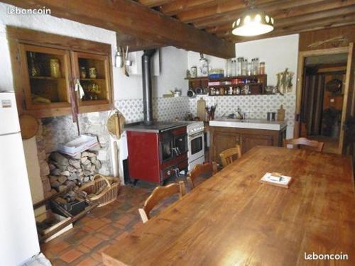 een keuken met een houten tafel en een open haard bij La Sauvagine in Les Fourgs