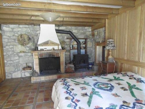 een slaapkamer met een stenen open haard en een bed bij La Sauvagine in Les Fourgs