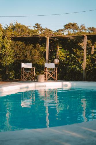 two chairs sitting under a gazebo next to a swimming pool at João Jungle in Açafora