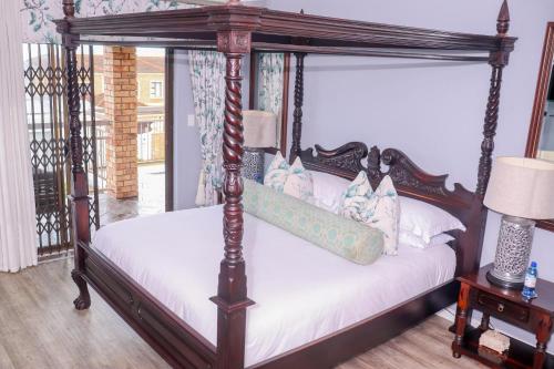 een slaapkamer met een hemelbed met witte lakens bij Nautilus Guesthouse in Port Elizabeth