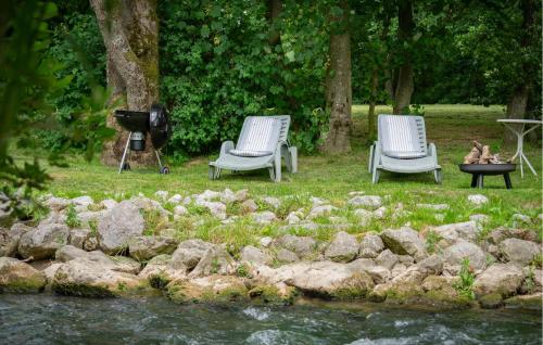 Twee stoelen en een tv naast een rivier. bij Ancien Moulin Restauré in Clerques