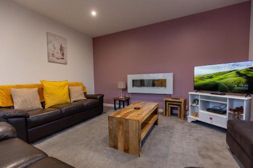 a living room with a couch and a flat screen tv at SHELTER STONE - Cottage in the heart of the Lakes in Keswick