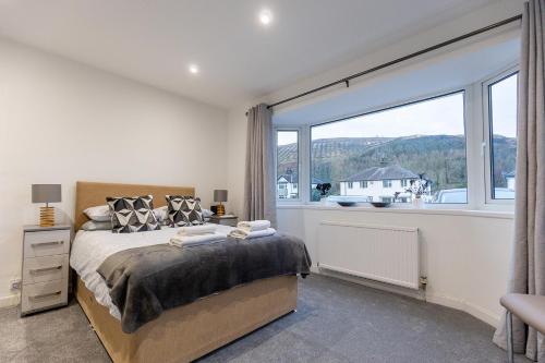 a bedroom with a bed and a large window at SHELTER STONE - Cottage in the heart of the Lakes in Keswick