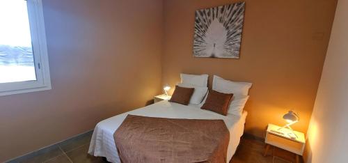 un dormitorio con una cama con sábanas y almohadas blancas en Ti Ker Créole, en Saint-Benoît