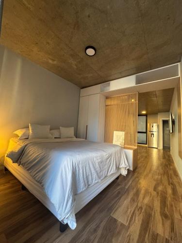a bedroom with a large bed and a wooden floor at Canela Loft Rosario in Rosario