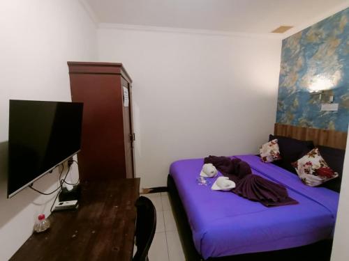 a small room with a purple bed and a desk at Ketapang Residence Hotel in Jakarta