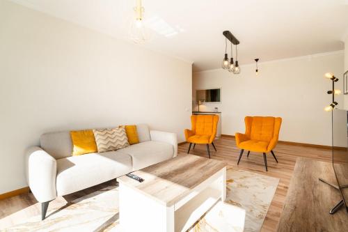 a living room with a white couch and orange chairs at GuestReady- Charming Condo with Pool in Caniço in Caniço