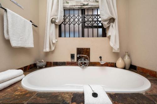 een groot wit bad in een badkamer met een raam bij Nautilus Guesthouse in Port Elizabeth