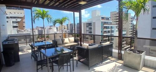 einen Balkon mit einem Tisch, Stühlen und Palmen in der Unterkunft Siberian Flat 204 Intermares in Cabedelo