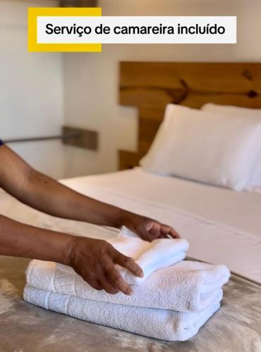 a person making a pile of towels on a bed at Residence Vespucci in Natal